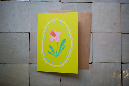 Greeting card with floral design on a yellow background, placed on a textured surface.