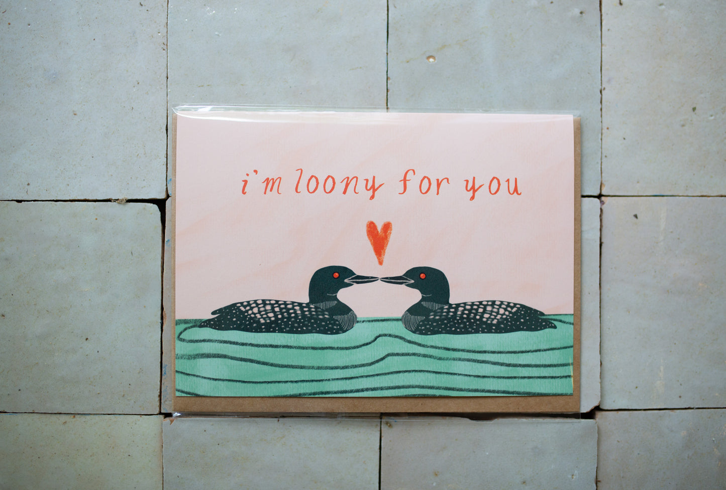 Greeting card on a tile floor that says I'm Loony for You with two loos facing each other with a heart in between them