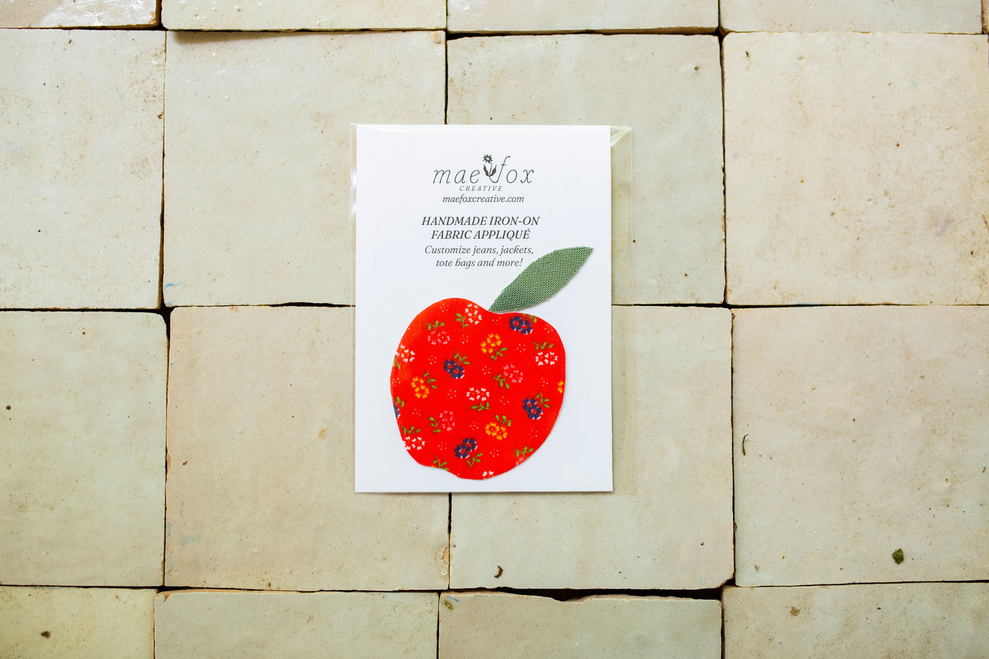 Handmade appliqué patch shaped like a apple, crafted from mixed vintage fabrics in rich red tones with a textured green leaf top, slightly imperfect, charming handmade finish, designed for decorating jackets, jeans, or tote bags.
