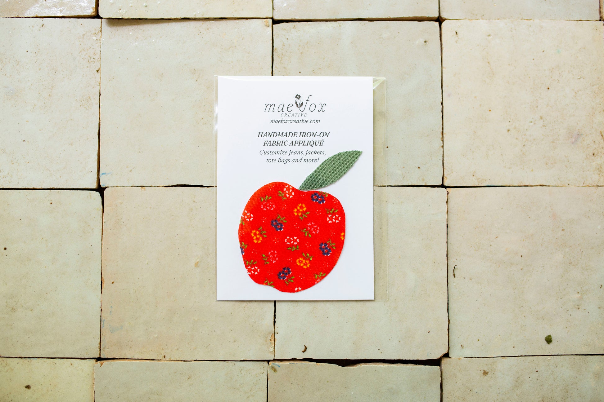 Handmade appliqué patch shaped like a apple, crafted from mixed vintage fabrics in rich red tones with a textured green leaf top, slightly imperfect, charming handmade finish, designed for decorating jackets, jeans, or tote bags.
