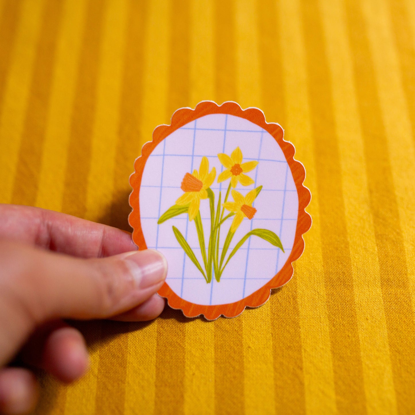 Hand holding a daffodil illustrated sticker