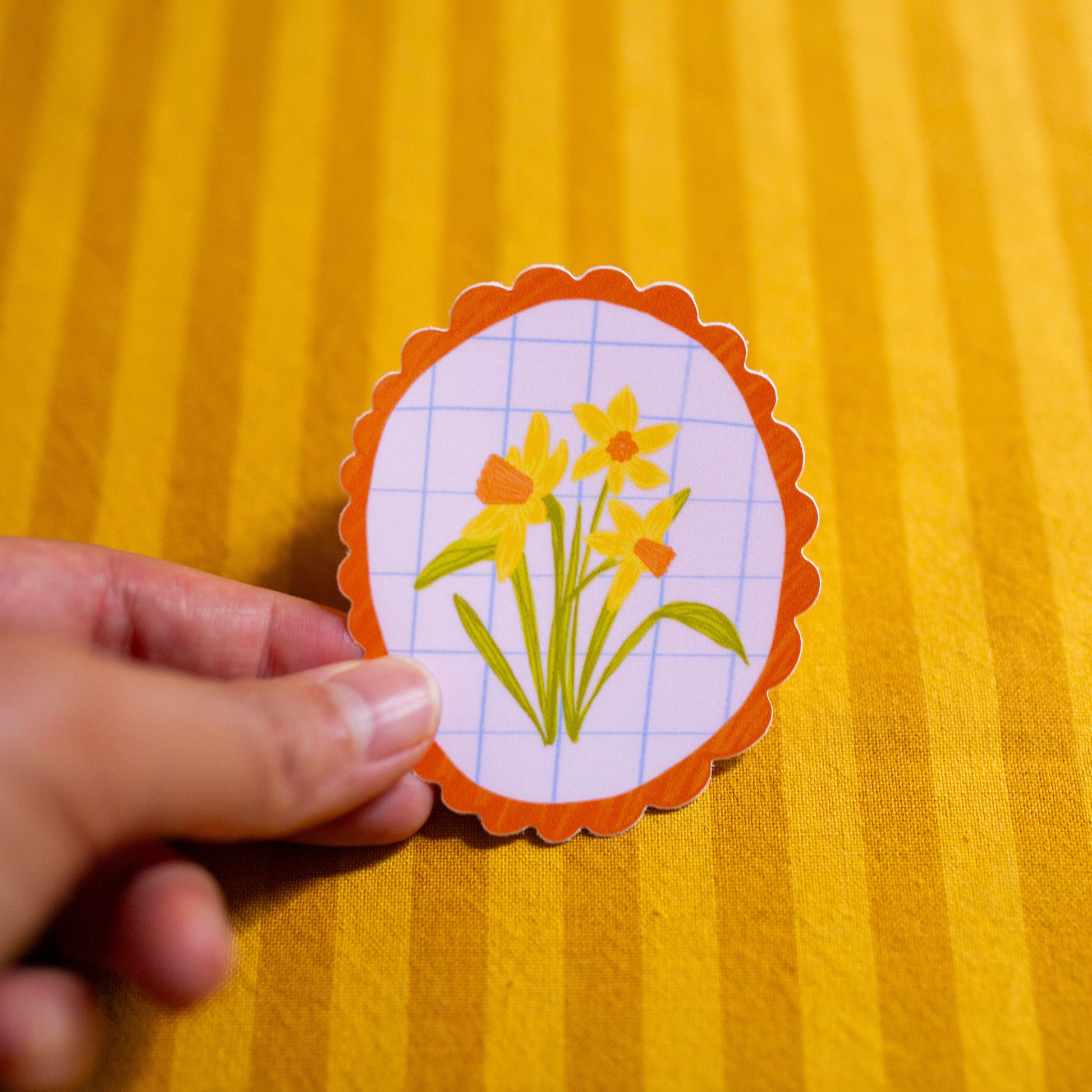 Hand holding a daffodil illustrated sticker