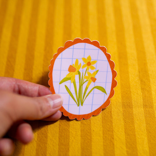 Hand holding a daffodil illustrated sticker
