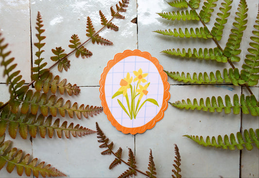 Daffodil vinyl sticker featuring a hand drawn yellow flower with orange scalloped border, perfect gift for plant and flower lovers.