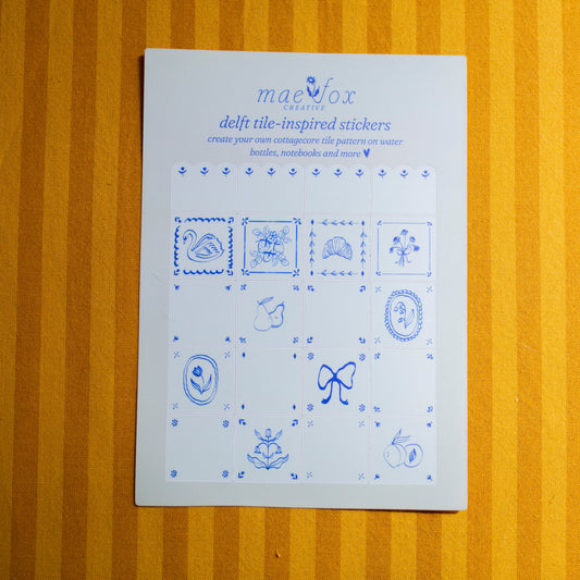Sheet of blue delft tile-inspired stickers on a fabric surface