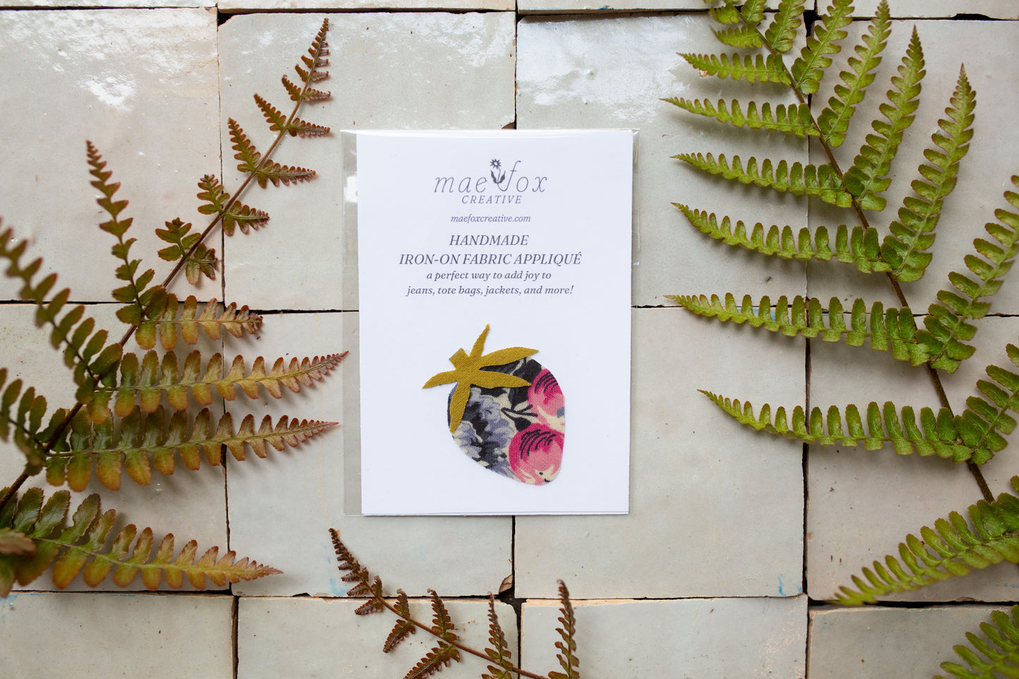 Handmade strawberry-shaped appliqué patch in floral purple and pink fabric with green leaf details