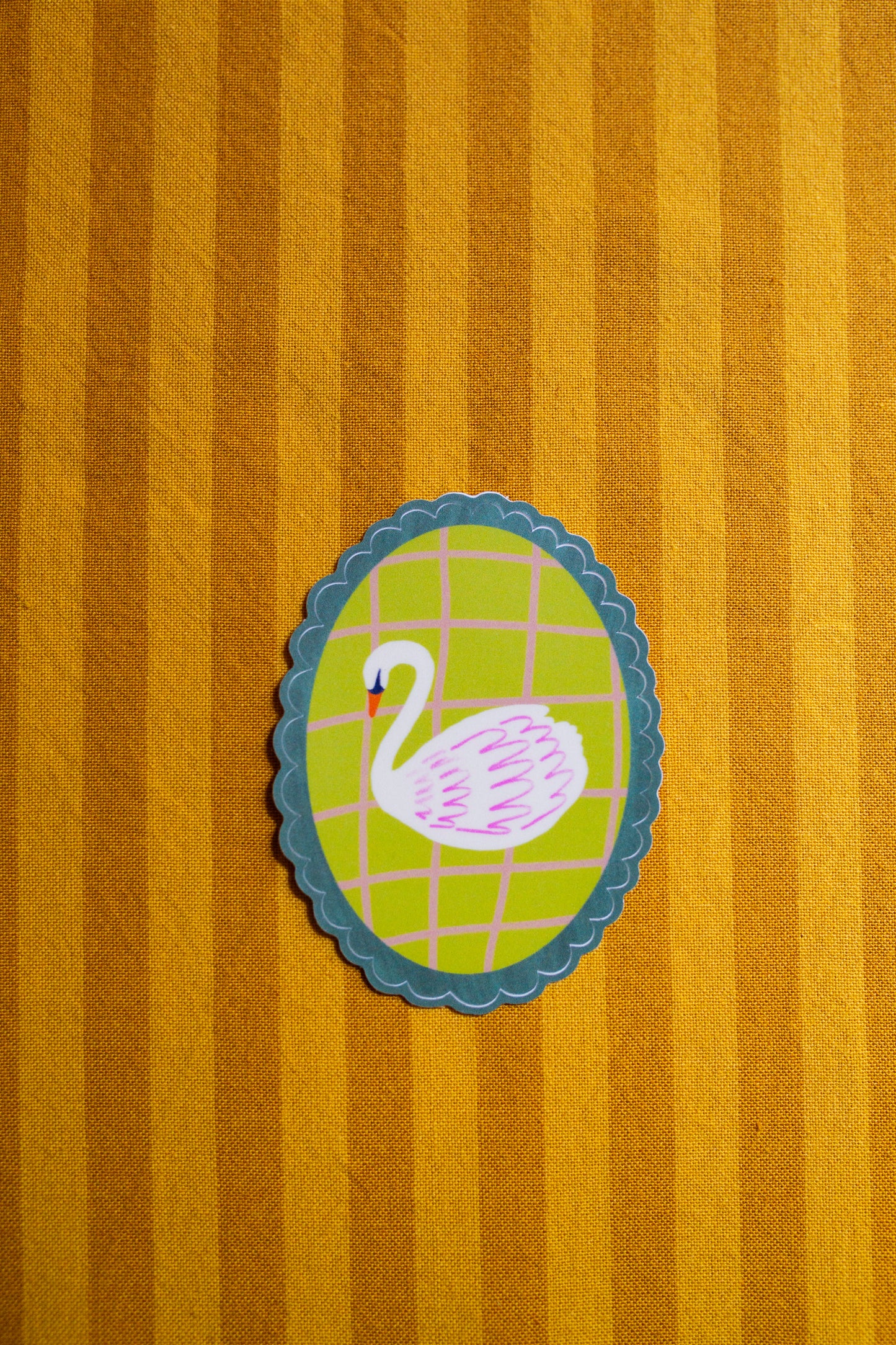 Decorative sticker of a swan on a striped fabric background