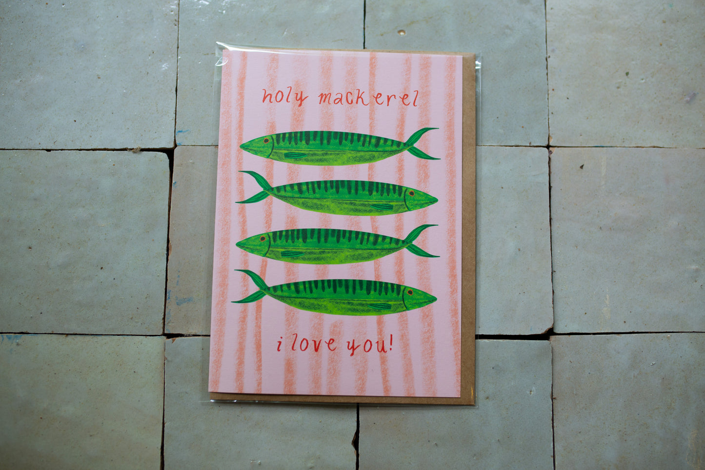 Greeting card with four green fish on a pink background that says "Holy Mackerel I love you!"