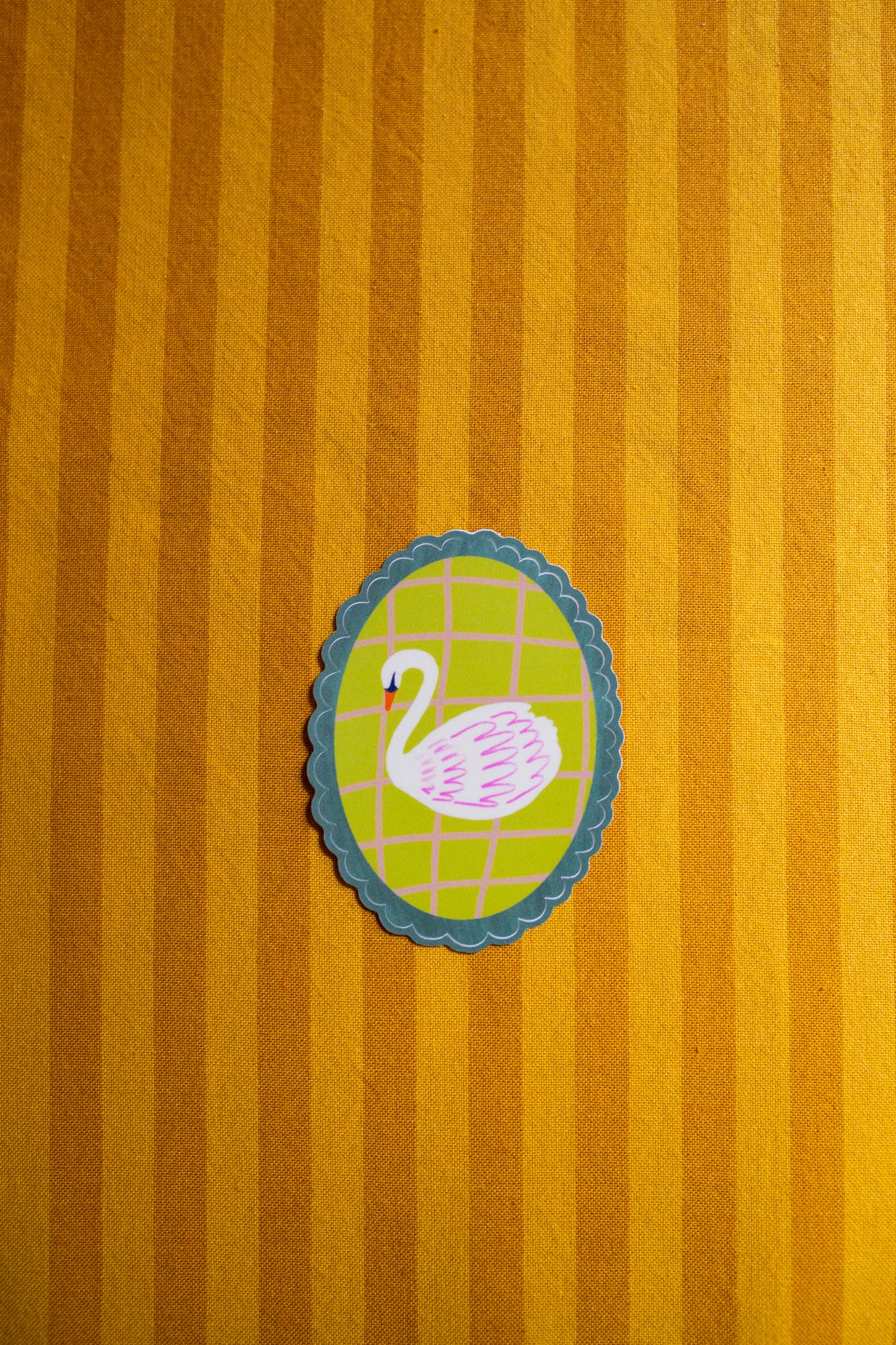 Decorative sticker of a swan on a yellow striped background