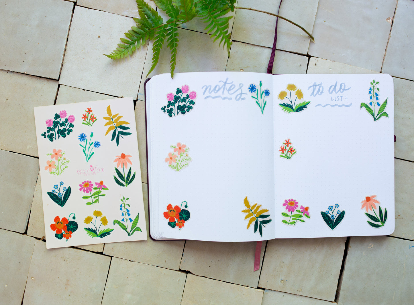 Open notebook with floral stickers on a tiled surface