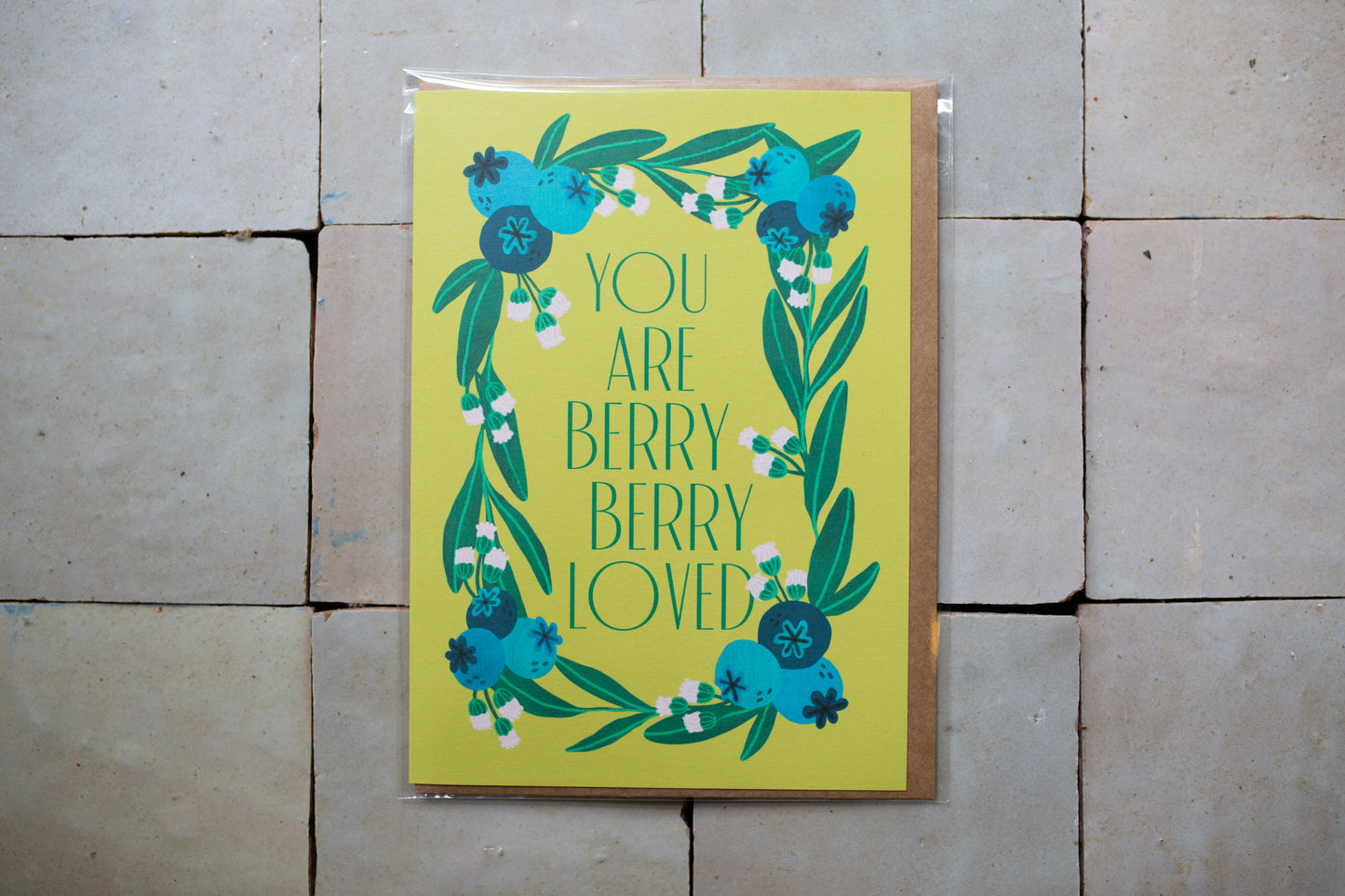 Card with blueberries on a yellow background that has words that say "You Are Berry Berry Loved"