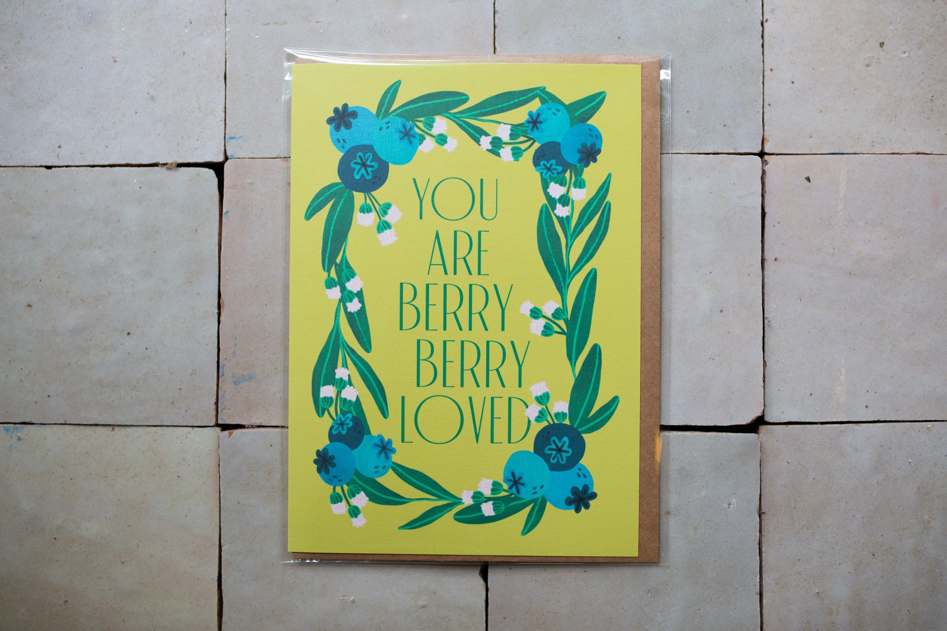 Card with blueberries on a yellow background that has words that say "You Are Berry Berry Loved"