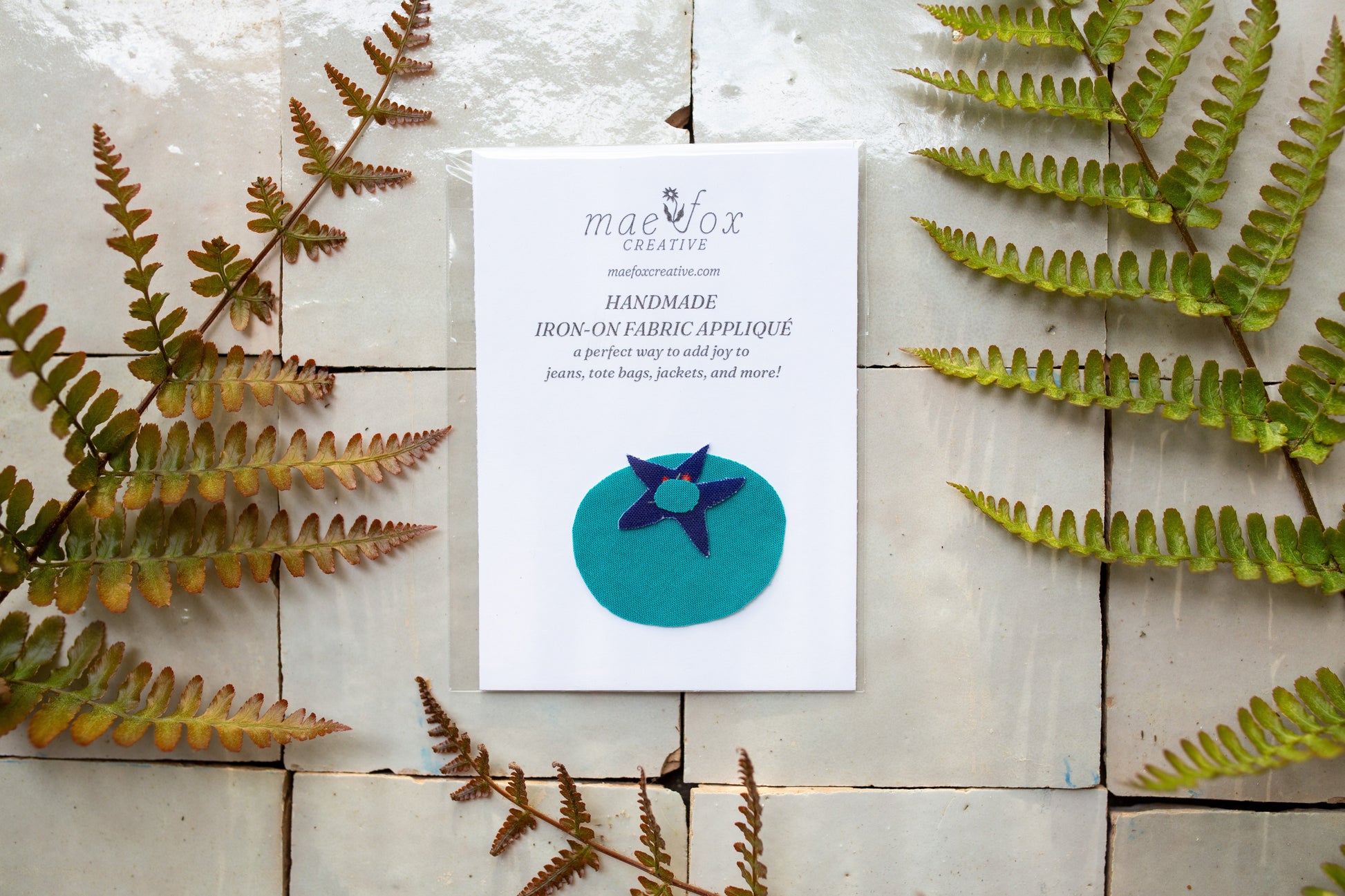 handmade applique patch shaped like a blueberry made with bright blue fabric and  dark floral fabric accent
