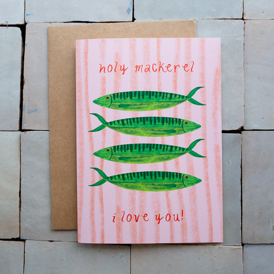Card with green fish illustrations and text on a pink background, placed on a stone surface.