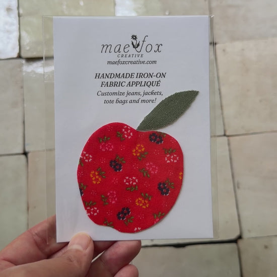 Handmade appliqué patch shaped like a apple, crafted from mixed vintage fabrics in rich red tones with a textured green leaf top, slightly imperfect, charming handmade finish, designed for decorating jackets, jeans, or tote bags.